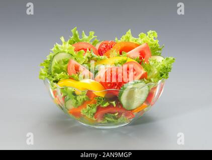 Eine Schüssel grünen Salat mit Tomaten, Gurken und Paprika auf grauem Hintergrund Stockfoto