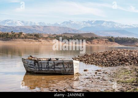 Holz- Boot am Ufer des Takerkoust See mit Atlas Gebirge im Hintergrund, Marrakesch, Marokko Stockfoto