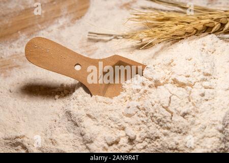 Eine hölzerne Schaufel in einem Haufen von Vollkornmehl ruht. Stockfoto