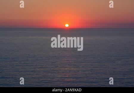 Sonnenuntergang über dem Meer, rot brennenden klarer Himmel, Horizont und dunklen, blauen Meer Oberfläche Stockfoto