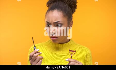 Junge weibliche Holding Wimpernzange und mascara Bürste, Beauty-Tipps überrascht Stockfoto