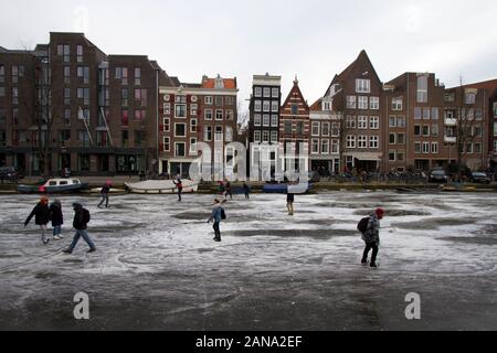 Menschen Schlittschuhlaufen auf zugefrorenen Grachten von Amsterdam im Winter 2018. Stockfoto