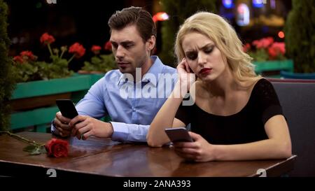 Zwei junge Leute langweilig auf Datum, mit Smartphones, Probleme in der Beziehung Stockfoto