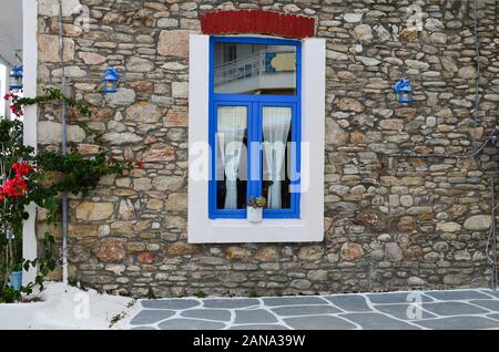 Blaues und weißes Fenster im griechischen Stil an der Steinwand, blaue Laternen und Blumen, Sommer auf der Insel Stockfoto