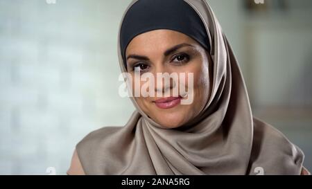 Bescheidene muslimischen Frau im hijab auf Kamera mit geheimnisvollen Lächeln, Nahaufnahme Stockfoto