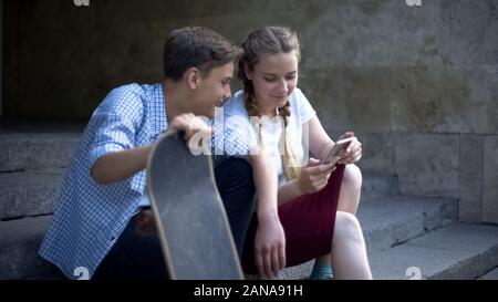 Lachen Skater beobachten tutorial video auf Handy, mobile Anwendung Stockfoto