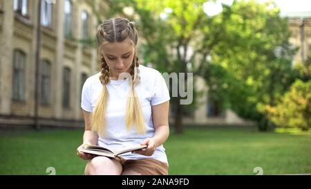 Schöne jugendlicher Mädchen Buch auf der Werkbank in Campus lesen, Hausaufgaben vorbereiten Stockfoto