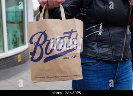 Junge Frau mit einem Stiefel der Chemiker Papier Shopping Bag UK Stockfoto