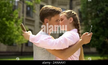 Paar mit Telefon, während das Umarmen, Neigung zu Social Networking Konzept Stockfoto