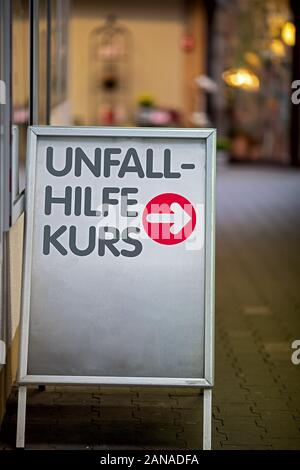 Schild mit roter Pfeil, der auf dem Weg zum Standort der Erste Hilfe Kurs, Text in deutscher Sprache Erste Hilfe Kurs Stockfoto