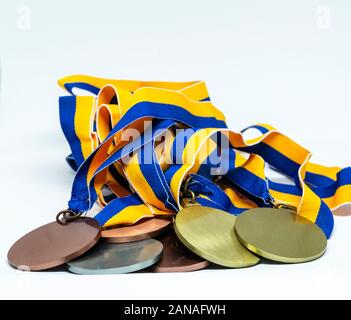 Eine Reihe von Gold-, Silber- und Bronzemedaillen mit Blau und Gold Ribbon zusammen auf einem weißen Hintergrund. Stockfoto