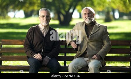 Zwei glückliche senior Freunde trinken Flaschenbier in Park, Erinnerung an junge Altersgruppen Stockfoto