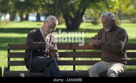 Alte Männer spielen Karten und Spaß im City Park, aktiven Lebensstil, Ruhestand Stockfoto