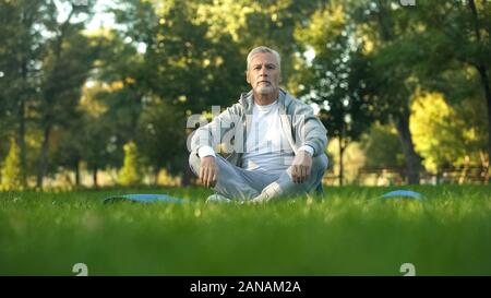 Sportliche reifer Mann Entspannung und Ruhe im Park, sitzen Lotussitz Yoga Matte Stockfoto