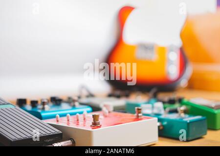 Guitar Pedal auf dem Boden einer Recording Studio, E-Gitarre im Hintergrund. Generische Gitarre Effekte auf dem Holzboden. Gitarrenmusik, Stockfoto