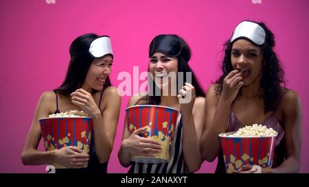 Drei Mädchen mit augenmasken Essen Popcorn und vor Lachen, laut, lustige Komödie Stockfoto