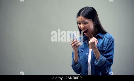 Asiatische Dame holding Smartphone, aufrichtig freuen, günstige Tarife für Anrufe Stockfoto