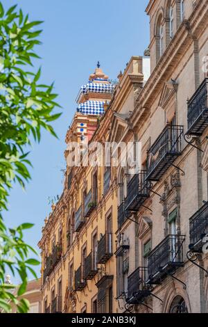 Leuchtend blaue und weiße Fliesen übertönen ein farbenfrohes Gebäude in der Calle Cuesta del Rosario, Sevilla Stockfoto