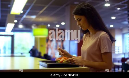 Junge Frau mit Mittagessen in der Kantine, Essen Salat sitzen cafe Tabelle Stockfoto