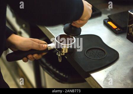 Barista Pressen gemahlenen Kaffee verwenden. Nahaufnahme auf Händen mit portafilter Stockfoto