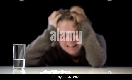 Stapel der weißen Pillen und Wasser Glas Tisch, ausweglose Gewalt Opfer Hintergrund Stockfoto