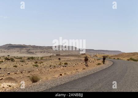 Leere Straße im südlichen Marokko mit blauem Himmel und die Berge im Hintergrund Stockfoto