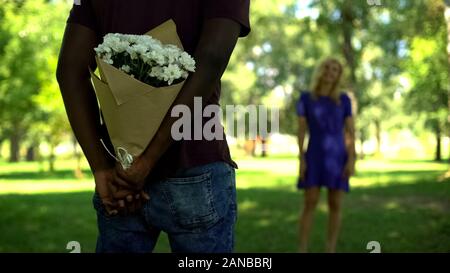 Afro-amerikanischen Freund ausblenden blumen blumenstrauss hinter Zurück im Park, lassen Sie sich überraschen Stockfoto