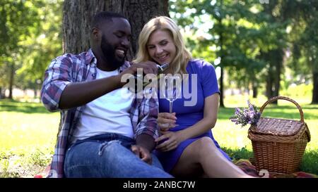 Fürsorglichen Mann gießen Rotwein zu womans Glas auf ein Picknick im Park, romantisches Date Stockfoto