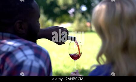 Rückansicht des glücklichen Paares gießen Wein im Glas, Feier Jubiläum im Freien Stockfoto