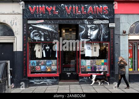 Eine Frau und ihr Hund Spaziergänge durch Vinyl Villans, eine unabhängige Datensätze gespeichert Verkauf von neuen und gebrauchten Schallplatten und CDs auf Elm Row, Edinburgh, Schottland. Stockfoto