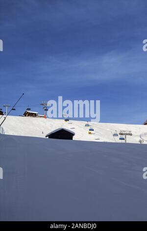 Verschneite Skigebiet mit Schnee grooming Maschine, Sesselbahn und Schneekanonen im Skigebiet vorbereitet. Berge im sonnigen Winter am frühen Morgen. Italienische Alpen. Stockfoto