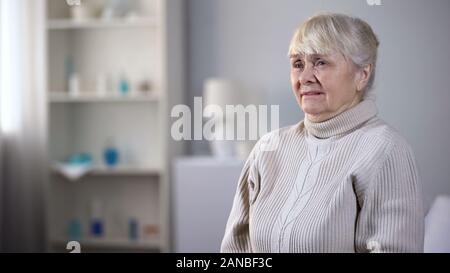 Miserable ältere Dame sitzt allein in der Krankenpflege Haus und schreien, Depression Stockfoto