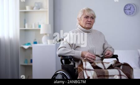 Reife Lady im Rollstuhl leiden unter Schmerzen halten Medikamente, Pflegeheim Stockfoto