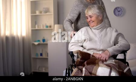 Tochter kümmert sich um ältere Mutter im Rollstuhl, Betreuer helfen Patienten Stockfoto