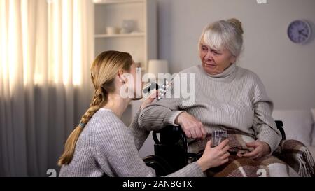 Frau mit Medizin zu kranken Großmutter, Pillen und Wasser Glas Stockfoto