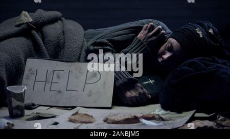 Bettler auf der Straße liegend mit Bibel, Hilfe Wort auf Karton, für Nächstenliebe Stockfoto