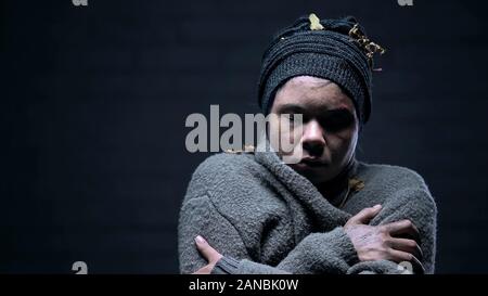 Obdachlose Frau geschlossenen Augen leiden Kälte auf dunklem Hintergrund, deprimiert Bettler Stockfoto