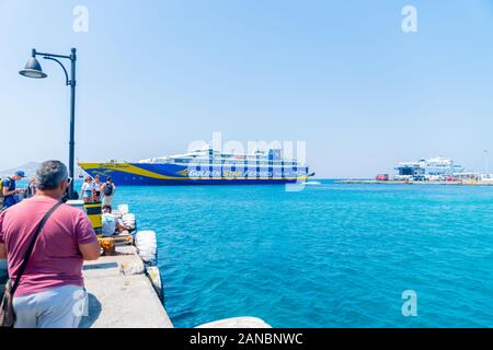 Naxos, Griechenland - 14 August 2019; Griechenland Kykladen Insel mit Fähren im Hafen, während die Menschen auf der nächsten Wharf watch Ankunft und Abreise. Stockfoto