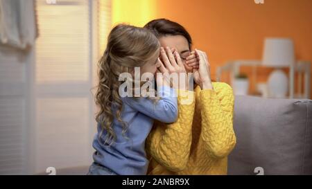 Adorable kleine Mädchen schließen Mütter Augen mit den Händen, glückliche Familie Momente Stockfoto