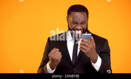 Extrem glücklich afrikanisch-amerikanischen Mann, Telefon und machen ja Geste, win Stockfoto