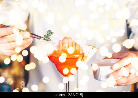 Barkeeper Dekoration Cocktail in einem Nachtclub. Nachtleben und Unterhaltung Konzept. Horizontale, Fett Licht bokeh Stockfoto