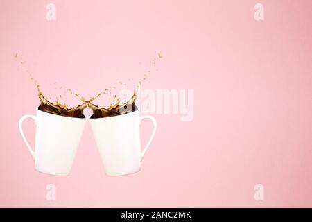 Zwei schwebenden Kaffeetassen mit Spritzern und Herz Konfetti. Kaffee Konzept. Minimal Art Trend. Solide Hintergrund. Horizontale Stockfoto