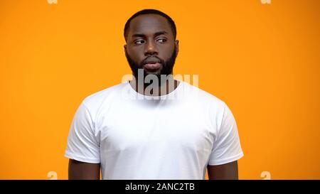 Beschämt Afrikaner - Mann, gegen den gelben Hintergrund zu Seite, schuldig Stockfoto