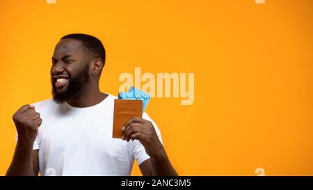 Happy afro-amerikanischer Mann, Reisepass, Flugtickets und ja Geste Stockfoto