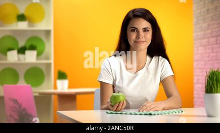 Lächelnd hübsche Frau mit grünen Apfel in der Hand, Gesundheitswesen, vegetarische Ernährung Stockfoto