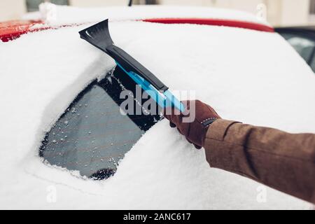 Auto Reinigung von Schnee mit Besen. Man kümmert sich um automobile Eis entfernen Mit Pinsel im Freien Stockfoto