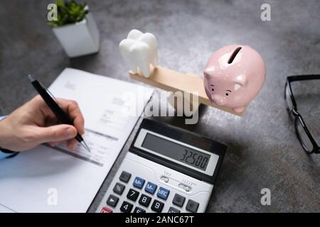 Zahnmedizinische Kosten einsparungen Konzept. Zahn und Sparschwein auf Wippe Stockfoto