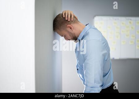 Portrait von Enttäuscht Geschäftsmann lehnte sich an der Wand im Büro Stockfoto