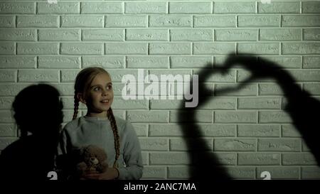 Mädchen auf Herz Schatten an der Wand und das Umarmen Teddybär, der Hoffnung und der Barmherzigkeit Stockfoto