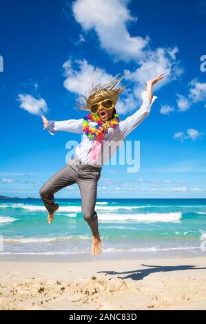 Tanzen Geschäftsmann auf Urlaub Sonnenbrille tragen, touristische Strohhut und lei Feiern auf einem tropischen Strand Stockfoto